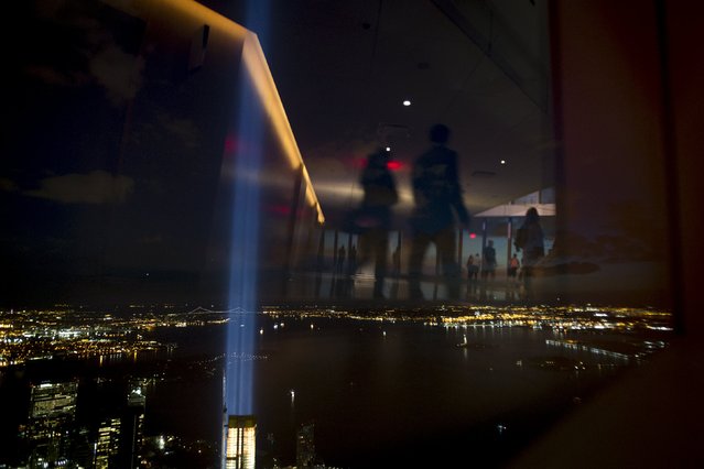 People are reflected in the windows at One World Observatory, the observation deck at One World Trade Center, as the Tribute in Light installation shines in Lower Manhattan in New York, September 11, 2015. People visited the recently opened viewing destination on Friday, which marked the 14th anniversary of the 9/11 attacks. The Tribute in Light is an annually lit feature commemorating the attacks. (Photo by Andrew Kelly/Reuters)