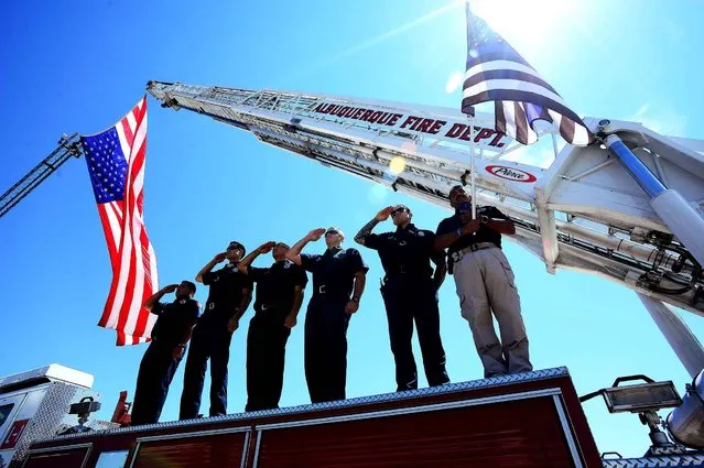 Albuquerque firefighters and police department chaplain stand on top of a ladder truck to salute the hearse carrying the body of Hatch Police Officer Jose Chavez, who was gunned down during a traffic stop Friday, in Albuquerque, N.M., Monday, August 15, 2016. (Photo by Adolphe Pierre-Louis/The Albuquerque Journal via AP Photo)
