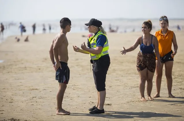 A police officer advises a swimmer to come in as the tide moves in on Camber Sands on August 25, 2016 in Rye, England. Five men were found dead after being pulled from the sea on the hottest day of the year yesterday in Camber Sands, East Sussex. (Photo by Jack Taylor/Getty Images)