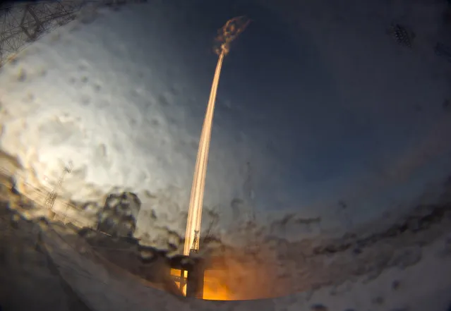 In this photo taken with a long exposure through the lens covered by frozen water, a Russian Soyuz 2.1b rocket carrying a Meteor M satellite and additional 18 small satellites lifts off from the launch pad at the new Vostochny cosmodrome outside the city of Tsiolkovsky, about 200 kilometers (125 miles) from the city of Blagoveshchensk in the far eastern Amur region, Russia, Tuesday, November 28, 2017. (Photo by Dmitri Lovetsky/AP Photo)