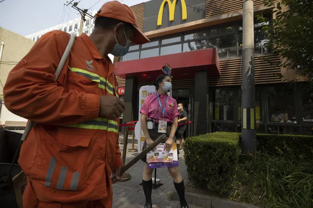 A worker wearing mask to curb the spread of the coronavirus waits to guide visitors to a McDonald's fast-food restaurant in Beijing on Monday, July 20, 2020. China has managed to contain the coronavirus outbreak even as the numbers of infection surge around the world. (Photo by Ng Han Guan/AP Photo)