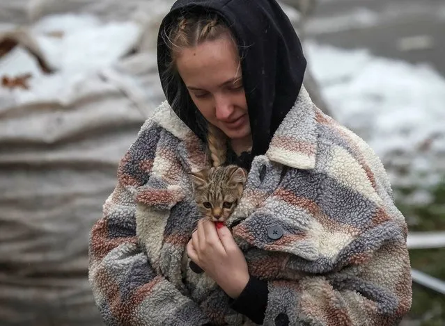 A local resident carries a kitten found in her flat in a residential building destroyed by a Russian missile attack, as Russia's attack on Ukraine continues, in the town of Vyshhorod, near Kyiv, Ukraine on November 24, 2022. (Photo by Gleb Garanich/Reuters)