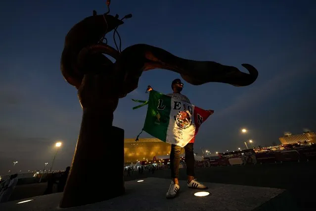 A Mexico fan holds the national flag prior to the start of the World Cup group C soccer match between Saudi Arabia and Mexico, at the Lusail Stadium in Lusail, Qatar, Wednesday, November 30, 2022. (Photo by Luca Bruno/AP Photo)