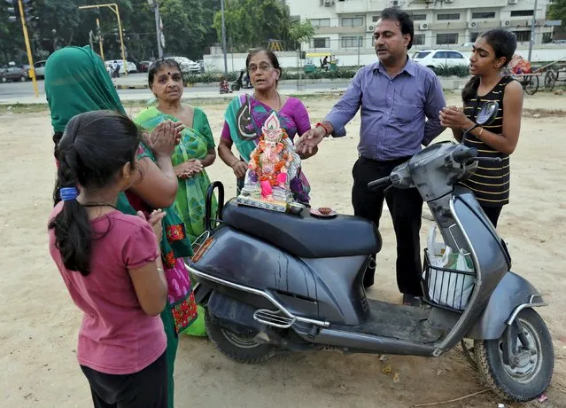 Family members pray around an idol of the Hindu god Ganesh, the deity of prosperity, placed on a scooter before its immersion during the ten-day-long Ganesh Chaturthi festival in Ahmedabad, India, September 22, 2015. (Photo by Amit Dave/Reuters)