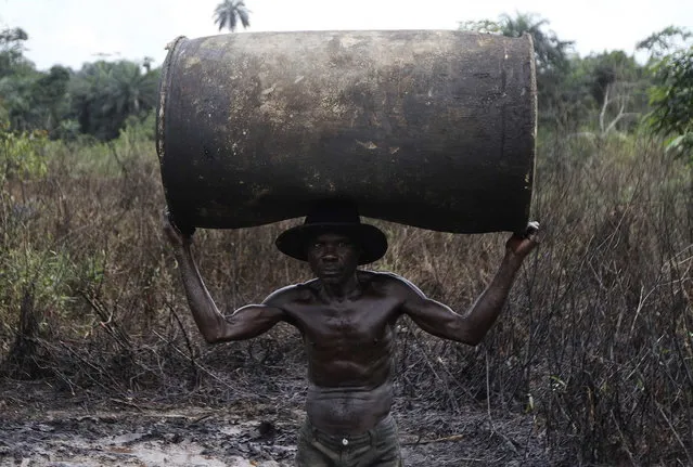 Ebiowei, 48, carries an empty oil container on his head to a place where it would be filled with refined fuel at an illegal refinery site near river Nun in Nigeria's oil state of Bayelsa November 27, 2012. (Photo by Akintunde Akinleye/Reuters)