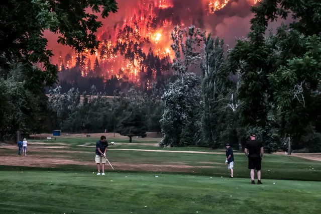 The Eagle Creek wildfire burns as golfers play at the Beacon Rock Golf Course in North Bonneville, Washington, September 4, 2017. (Photo by Kristi McCluer/Reuters)