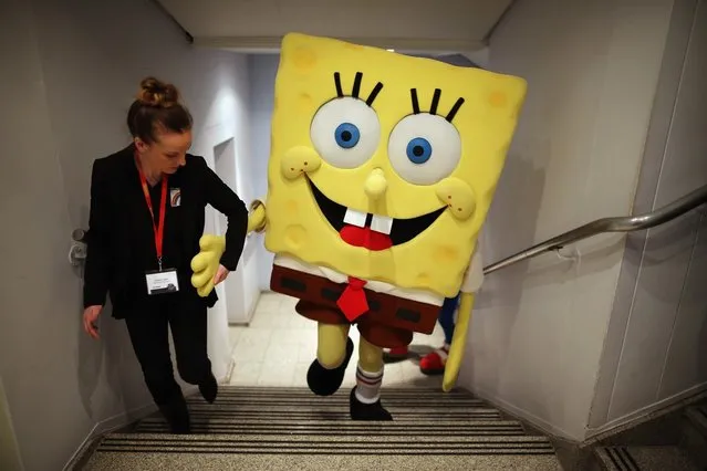 A Sponge Bob Square Pants character is helped up a flight of stairs  during the 2013 London Toy Fair at Olympia Exhibition Centre on January 22, 2013 in London, England. The annual fair which is organised by the British Toy and Hobby Association, brings together toy manufacturers and retailers from around the world.  (Photo by Dan Kitwood)