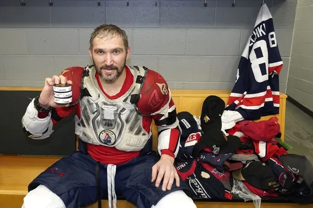 Washington Capitals' Alex Ovechkin holds his 798, 799, and 800th career goal pucks in the locker room next to hats collected for his hat trick after an NHL hockey game against the Chicago Blackhawks Tuesday, December 13, 2022, in Chicago. (Photo by Charles Rex Arbogast/AP Photo)