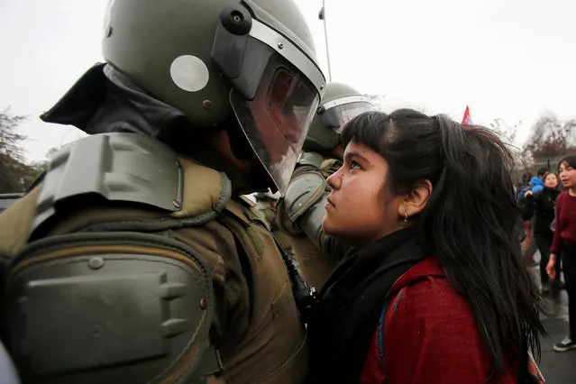 A demonstrator looks at a riot policeman during a protest marking the country's 1973 military coup in Santiago, Chile September 11, 2016. (Photo by Carlos Vera/Reuters)