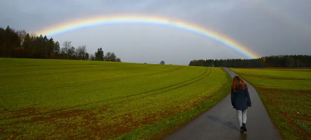 A young woman walks in front of a rainbow in Behla, Germany, March 30, 2015. (Photo by Patrick Seeger/EPA)