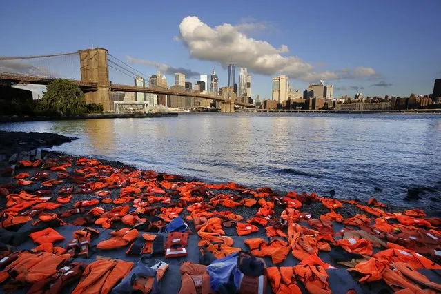 Advocates with Oxfam America have placed hundreds of life jackets on the ground along the New York City waterfront to draw attention to the refugee crisis, Friday, September 16, 2016, in the Brooklyn borough of New York. Many of the life jackets used for the Friday action were used by adult and child refugees and collected on beaches in Greece. The undertaking was a prelude to next week's United Nations Summit for Refugees and Migrants. (Photo by Mark Lennihan/AP Photo)