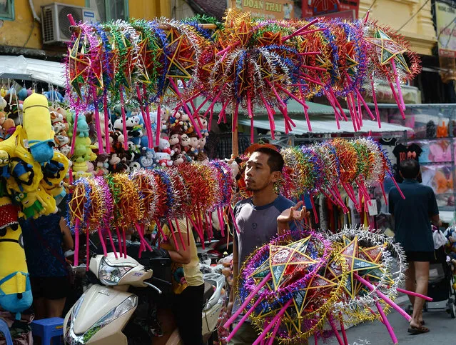 This picture taken on September 23, 2015, shows a vendor carrying a large bunch of star-shaped lanterns for sale at a local traditional mid-autumn festival toy market in downtown Hanoi. (Photo by Hoang Dinh Nam/AFP Photo)