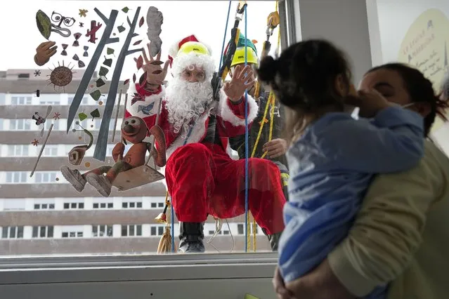 A Santa hangs down the facade of the Hospital Germans Trias i Pujol, with the help of the Charity Firemen of Barcelona, as he visits children admitted to the medical center, in Barcelona, Spain, 19 December 2022. (Photo by Alejandro Garcia/EPA/EFE)