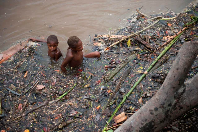 Papuan children swim at dirty river water at the village of Ayam in Agats, the capital of Asmat district in Indonesia' s easternmost Papua province, on January 26, 2018. Some 800 children have been sickened in the area with as many as 100 others, mostly toddlers, feared to have died in what a military official called an “extraordinary” outbreak that was first made public this month. (Photo by Bay Ismoyo/AFP Photo)