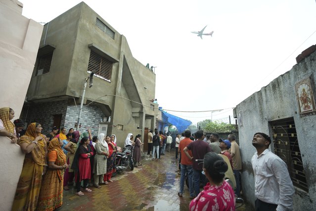 People waits for the funeral procession for Rajendra Patankar, a victim of the Air India plane crash, as a plane takes off from the airport in Ahmedabad, India, Thursday, June 19, 2025. (Photo by Ajit Solanki/AP Photo)