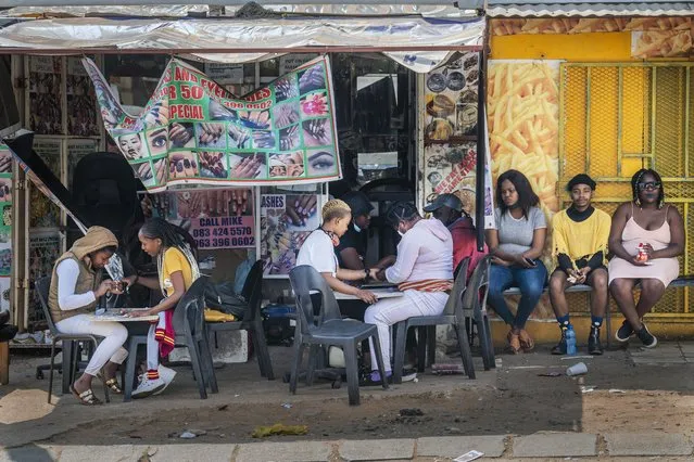 Customers have their nails done near the Baragwanath taxi rank in Soweto, South Africa, Wednesday September 16, 2020. South African president Cyril Ramaphosa is scheduled to address the nation later in the day, as case numbers and death from Covid-19 hit the lowest in months. (Photo by Jerome Delay/AP Photo)