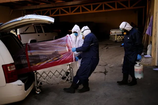 Employees of the Rios funeral home remove the body of a person who died from the coronavirus disease (COVID-19) from a hearse in Ciudad Juarez, Mexico on October 22, 2020. (Photo by Jose Luis Gonzalez/Reuters)