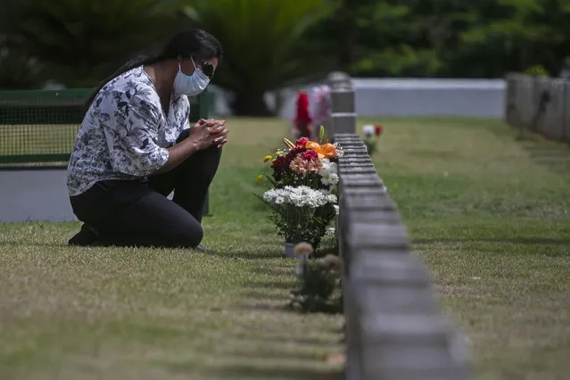 Vera Lucia Neia prays at the grave of her mother Maria Auxiliadora, 76, who she said died of COVID-19, on Day of the Dead at the Penitencia cemetery in Rio de Janeiro, Brazil, Monday, November 2, 2020. Brazil has confirmed more than 160,000 deaths from the virus, the second-highest in the world, behind only the U.S. (Photo by Bruna Prado/AP Photo)