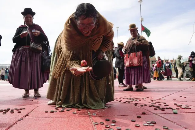 An Aymara woman plays with a spinning top during activities commemorating the anniversary of the founding of the city of El Alto, Bolivia, March 5, 2023. (Photo by Juan Karita/AP Photo)
