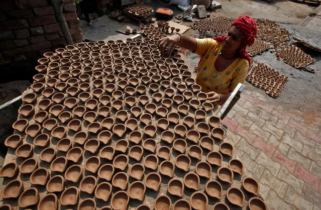 A woman arranges earthen lamps which are used to decorate homes during the Hindu festival of Diwali, to dry out in the sun at a workshop in Chandigarh, India, October 7, 2016. (Photo by Ajay Verma/Reuters)