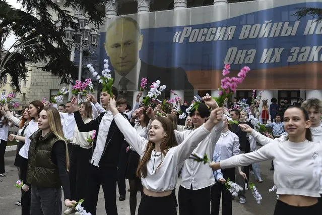 Youth take part in an action to mark the ninth anniversary of the Crimea annexation from Ukraine with the banner reads: “Russia doesn't start wars, it ends them” accompanied with an image of Russian President Vladimir Putin in Yalta, Crimea, Friday, March 17, 2023. (Photo by AP Photo/Stringer)