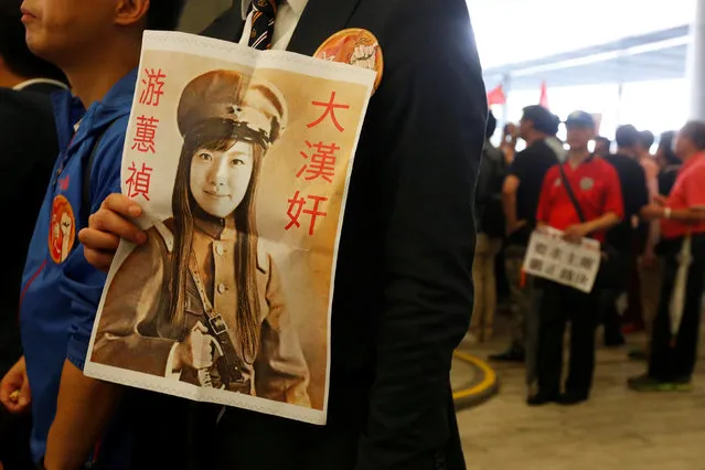 A protester carries a printout depicting legislator-elect Yau Wai-ching as a traitor during a demonstration outside the Legislative Council in Hong Kong, China October 19, 2016. (Photo by Bobby Yip/Reuters)