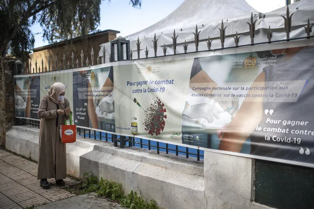 A woman wearing a face mask to prevent the spread of coronavirus walks past a bivouac where clinical trials for covid-19 vaccines are conducted, in Rabat, Morocco, Monday, December 7, 2020. (Photo by Mosa'ab Elshamy/AP Photo)