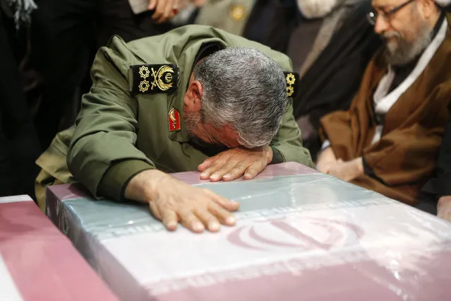 A handout picture provided by the office of Iran's Supreme Leader Ayatollah Ali Khamenei shows an unidentified Revolutianary Guard commander paying over the caskets of slain Iranian military commander Qasem Soleimani during a funeral ceremony at Tehran University in the Iranian capital on January 6, 2020. Mourners packed the streets of Tehran for ceremonies to pay homage to Soleimani, who spearheaded Iran's Middle East operations as commander of the Revolutionary Guards' Quds Force and was killed in a US drone strike on January 3 near Baghdad airport. (Photo by Iranian Supreme Leader's Website/AFP Photo)