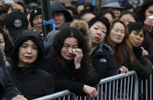 A woman wipes away tears as she and other mourners cram on the sidewalk to listen to the funeral service for New York Police Department officer Wenjian Liu in the Brooklyn borough of New York January 4, 2015. (Photo by Mike Segar/Reuters)