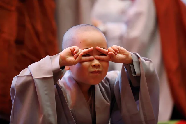 A novice monk reacts after getting his head shaved by a Buddhist monk during an event to celebrate the upcoming Vesak Day, birthday of Buddha, at Jogye temple in Seoul, South Korea, May 2, 2018. (Photo by Kim Hong-Ji/Reuters)
