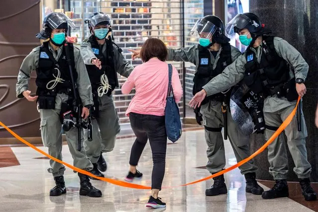 Riot police wear face masks, as a precautionary measure against the COVID-19 coronavirus, allow a women to cross a cordon after a protest by pro-democracy demonstrators at a shopping mall in Hong Kong on May 9, 2020. (Photo by Isaac Lawrence/AFP Photo)