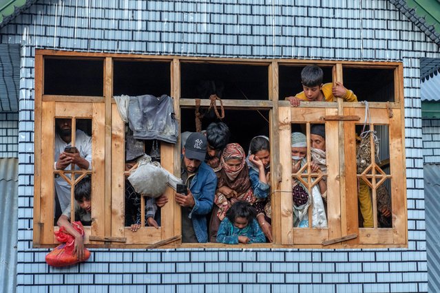 Kashmiri villagers watch from the window of a residential house the funeral of Mushtaq Ahmad, an army porter who was among those killed in a rebel ambush on an army vehicle on Thursday night, in Nowshera village north of Srinagar, Indian controlled Kashmir, Friday, October 25, 2024. (Photo by Dar Yasin/AP Photo)