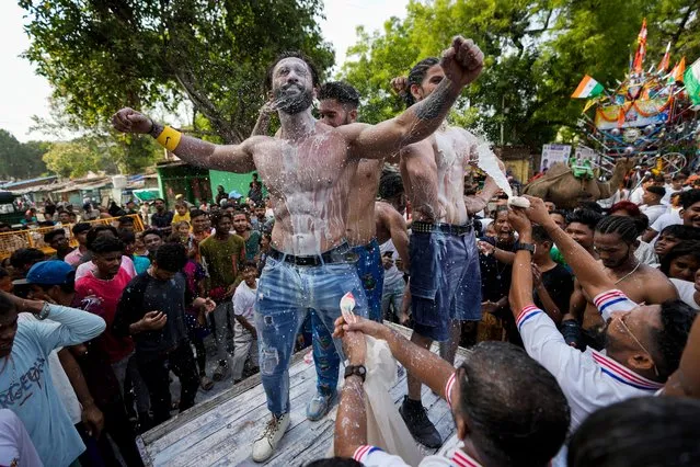 People pour milk on body builders as they participate in the annual chariot festival of Hindu god Lord Jagannath in Ahmedabad, India, Tuesday, June 20, 2023. (Photo by Ajit Solanki/AP Photo)