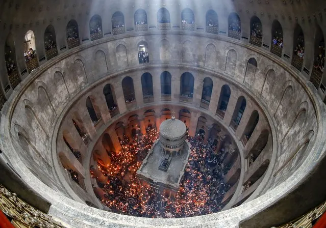 Orthodox Christians gather with lit candles around the Edicule, traditionally believed to be the burial site of Jesus Christ, during the Holy Fire ceremony at Jerusalem's Holy Sepulchre church, on April 23, 2022. (Photo by Ahmad Gharabli/AFP Photo)