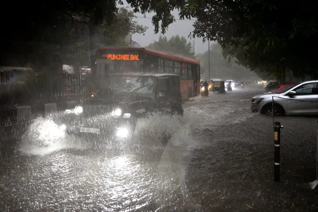 Vehicles move through a water logged street during a heavy downpour in New Delhi, India, Sunday, July 9, 2023. (Photo by Manish Swarup/AP Photo)