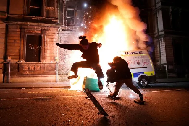 A demonstrator skateboards in front of a burning police vehicle during a protest against a new proposed policing bill, in Bristol, Britain, March 21, 2021. (Photo by Peter Cziborra/Reuters)