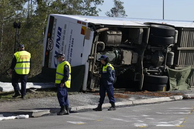 Police inspect a bus in its side near the town of Greta following a crash in the Hunter Valley, north of Sydney, Australia, Monday, June 12, 2023. The bus carrying wedding guests rolled over on a foggy night in Australia's wine country, killing and injuring multiple people, police said. (Photo by Mark Baker/AP Photo)