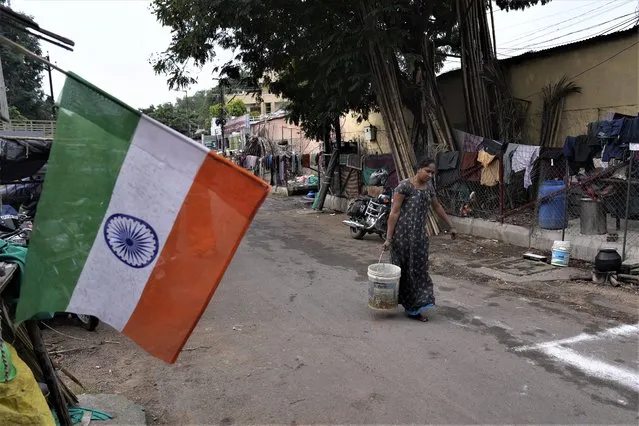 A woman carrying water walks at a slum where an Indian flag is displayed on Independence Day in Hyderabad, India, Tuesday, August 15, 2023. Prime Minister Narendra Modi said India’s economy will be among the top three in the world within five years, as he marked 76 years of independence from British rule on Tuesday. (Photo by Mahesh Kumar A./AP Photo)