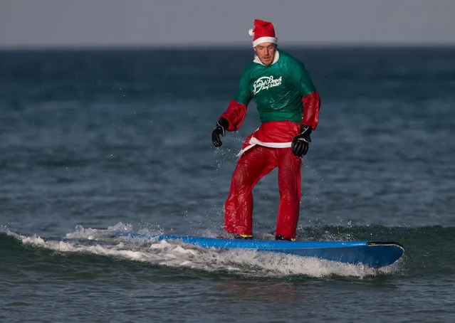 A surfer dressed as Santa gets to his feet as he braves the cold seas and near flat waves during the annual Surfing Santa as part of the Santa Run and Surf 2016 at Fistral Beach in Newquay on December 4, 2016 in Cornwall, England. (Photo by Matt Cardy/Getty Images)