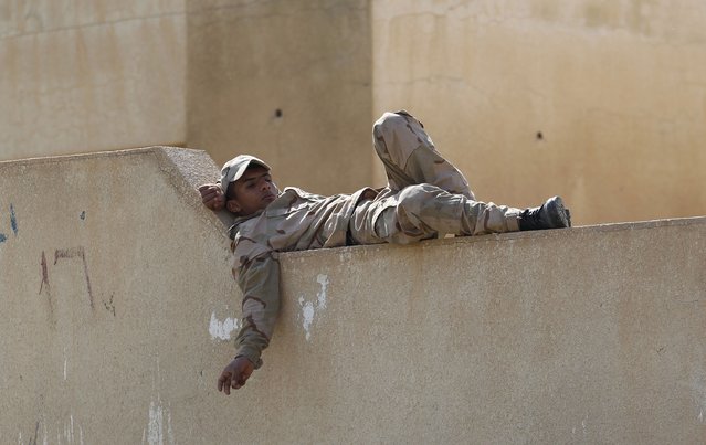 An Iraqi soldier rests on a wall at Udhaim dam, north of Baghdad March 1, 2015. Iraqi soldiers and pro-government Shi'ite militias had been massing in preparation for an attack on Islamic State strongholds along the Tigris River to the north and south of Tikrit, hometown of executed former president Saddam Hussein.    REUTERS/Thaier Al-Sudani 