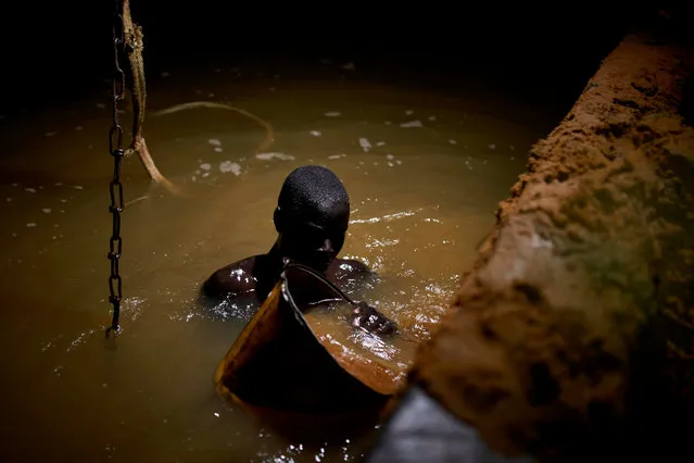 A Malian digger dives in the waters of the Niger River to check the quality of the sand, at a sand quarry near Kangaba in Mali' s southwestern Koulikoro region, on October 3, 2018. (Photo by Michele Cattani/AFP Photo)