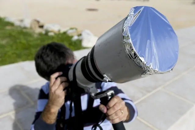A man has aluminium foil stretched over the lens of his camera as he tries to take images of a rare solar eclipse showing the Sun partially blocked by the Moon passing in front, in Estoril near Lisbon, Portugal, 03 November 2013. (Photo by Miguel A. Lopes/EPA/EFE)