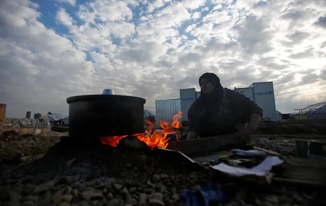 A displaced Iraqi woman, who fled the Islamic State stronghold of Mosul, cooks food at Hassan Sham camp, east of Mosul, Iraq December 27, 2016. (Photo by Khalid al Mousily/Reuters)