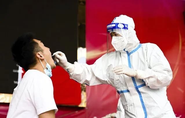 In this photo released by Xinhua News Agency, a medical worker collects a swab sample for nucleic acid test in Ruili City of southwest China's Yunnan Province, on July 5, 2021. Authorities in the Chinese city bordering Myanmar locked down the city Wednesday, July 7, shutting most businesses and requiring residents to stay at home, as a fresh outbreak of COVID-19 expanded. (Photo by Wang Guansen/Xinhua via AP Photo)