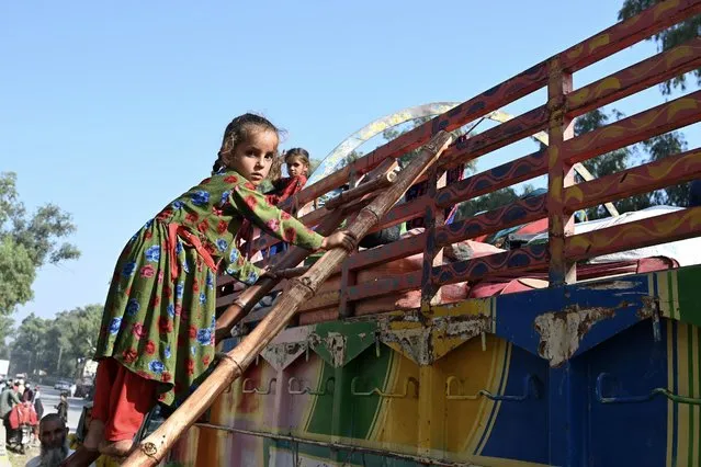 An Afghan refugee girl living in Pakistan climbs a ladder onto a truck outside the United Nations High Commissioner for Refugees (UNHCR) repatriation center, some 25 Km from Peshawar on October 25, 2023, as she returns with her family to Afghanistan following Pakistan's government decision to expel people illegally staying in the country. Hundreds of thousands of Afghans living illegally in Pakistan have been given until November 1 to leave voluntarily or face deportation, the interior minister said on October 3, a crackdown Kabul's embassy in Islamabad called “harassment”. (Photo by Abdul Majeed/AFP Photo)