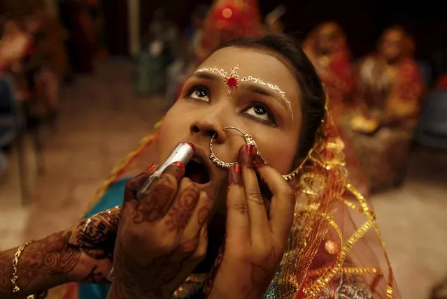 A bride gets her make-up done before the start of a mass marriage ceremony in Kolkata, India, February 14, 2016. A total of 150 tribal Hindu, Muslim and Christian couples from various villages across the state took their wedding vows on Sunday during the day-long mass marriage ceremony organised by a social organisation, the organisers said. (Photo by Rupak De Chowdhuri/Reuters)