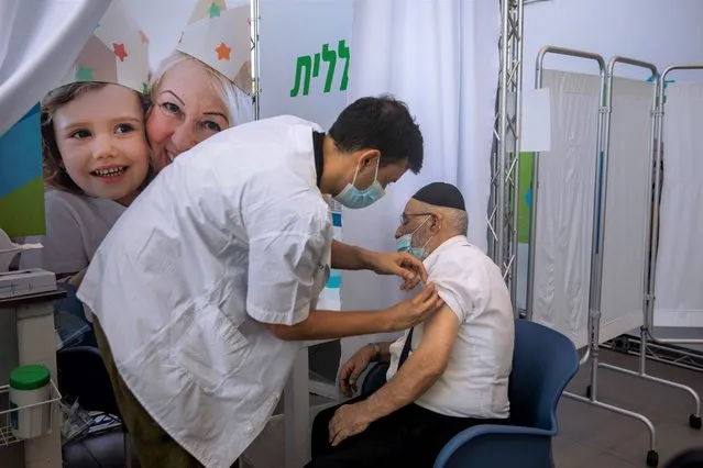 A man receives a third Pfizer-BioNTech COVID-19 vaccine from medical staff at a coronavirus vaccination center in Tel Aviv, Israel, Tuesday, August 10, 2021. Israel is grappling with a surge of infections and urging people over age 60 to get a booster shot. (Photo by Oded Balilty/AP Photo)