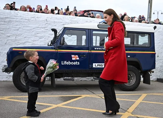 Britain's Catherine, Princess of Wales reacts as she is presented with a posy of flowers by four-year-old Theo Crompton during a visit to the RNLI (Royal National Lifeboat Institution) Holyhead Lifeboat Station in Anglesey, north west Wales on September 27, 2022. (Photo by Paul Ellis/Pool via AFP Photo)