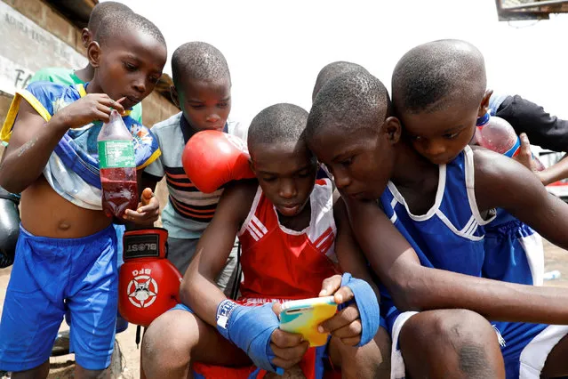 Kid boxers watch a video on a mobile phone together after a training session at the boxing gym in Adura playground, in Lagos, Nigeria on June 5, 2021. (Photo by Temilade Adelaja/Reuters)