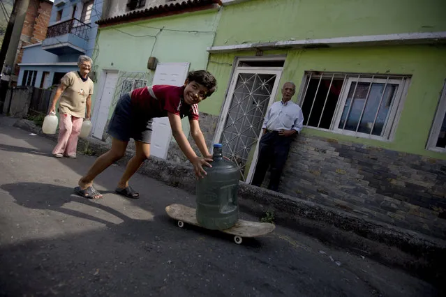 Cotiza neighborhood residents carry water from a public fountain a day after isolated protest against Venezuela's President Nicolas Maduro, in Caracas, Venezuela, Tuesday, January 22, 2019. Working class neighborhoods in Venezuela's capital sifted through charred rubble and smoldering trash on Tuesday, following a day of violence erupting in the streets. (Photo by Fernando Llano/AP Photo)